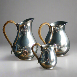 A beautiful trio set of silver plated jugs in midcentury style with wicker handles