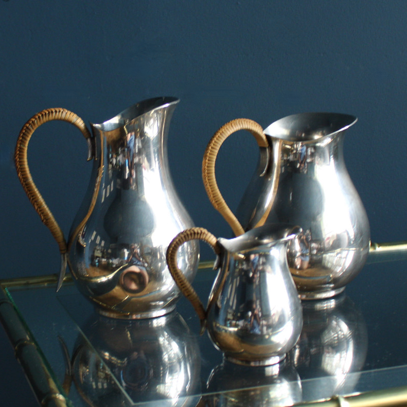 A beautiful trio set of silver plated jugs in midcentury style with wicker handles