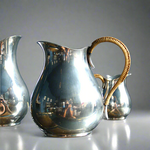 A beautiful trio set of silver plated jugs in midcentury style with wicker handles